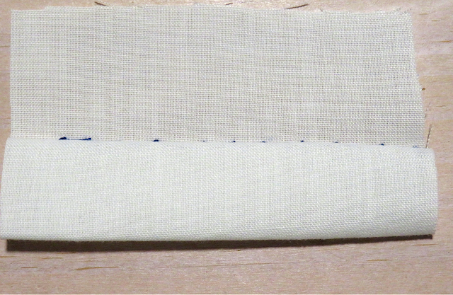 Puntada invisible con hilo azul sobre tela blanca por el revés