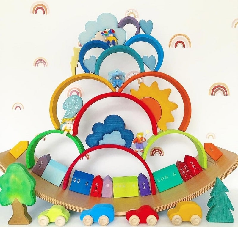 grimms rainbow and other toys stacked on top of a wobbel board