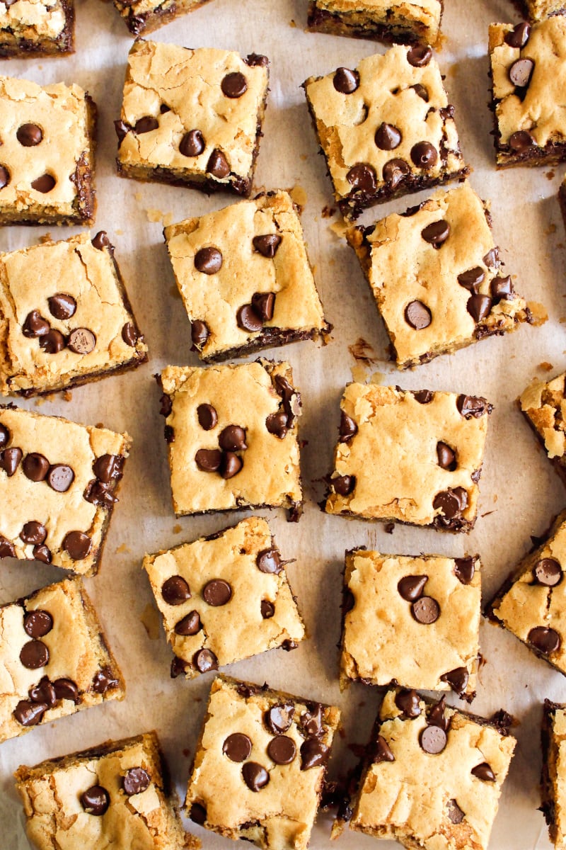 Brown Butter Chocolate Chip Cookie Bars | The Two Bite Club | #chocolate #cookiebars Top view of brown butter cookie bars squares on a piece of parchment paper.