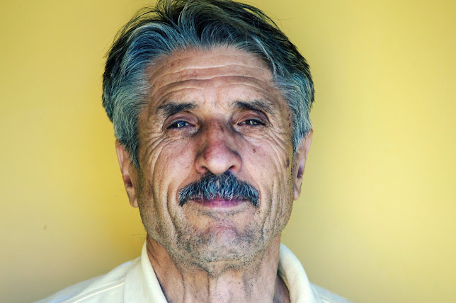 Image of a middle aged man looking straight down the camera lens; yellow background