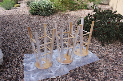 Round wood bar stools outside getting painted