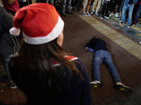 woman wearing a Santa cap looking at a man on the ground