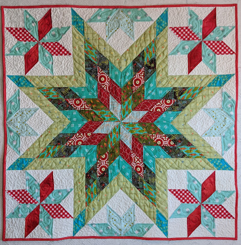 Main star in red, turquoise, black and green with smaller red and aqua stars around the sides