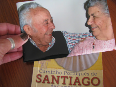 mão segurando a foto de um casal de idosos sobre o Guia do Caminho de Santiago