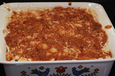 Tortilla layered and filled with melted cheese, meat and refried beans in a casserole dish baked