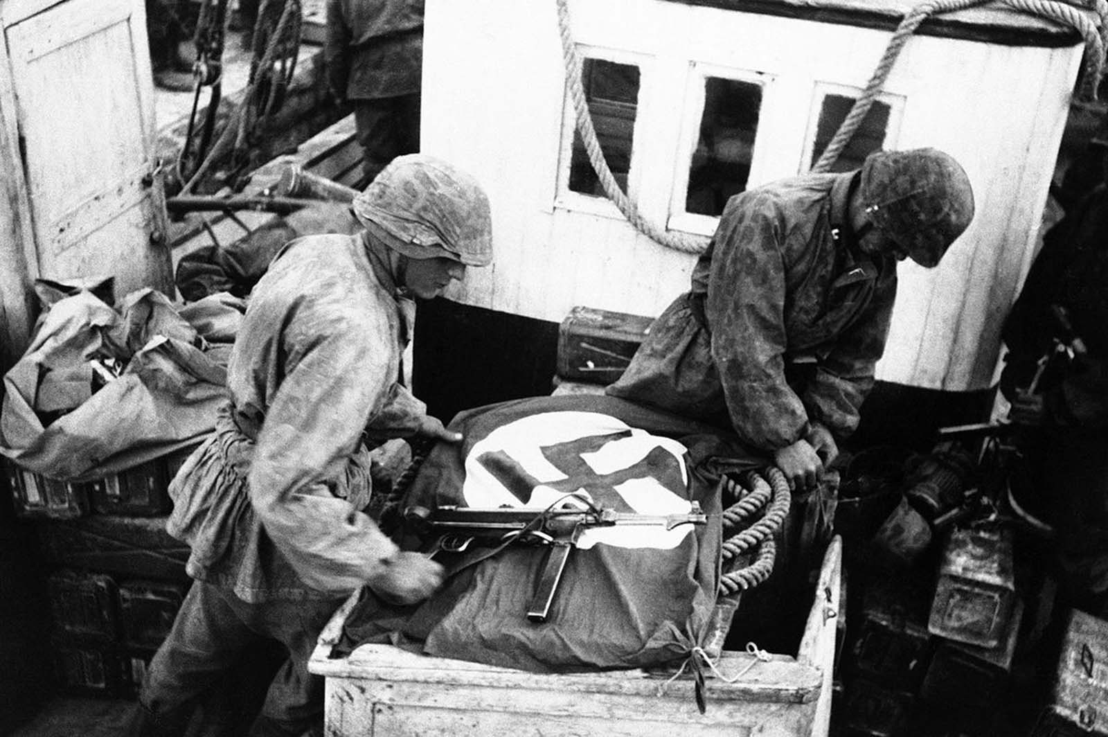 To alert their own airforce to their presence, soldiers spread the Swastika across boats used by the S.S. troops to cross the Gulf of Corinth, Greece, on May 23, 1941.