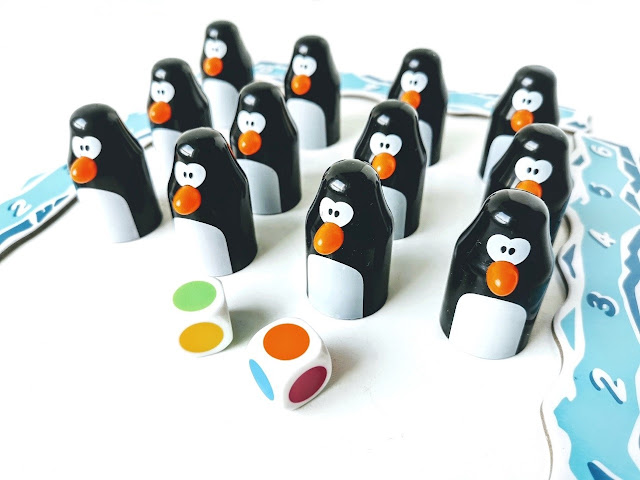 Najlepsza gra dla przedszkolaka, na zdjęciu zbliżenie pingwinów stojących po cztery w trzech rzędach, przed nimi leżą dwie kostki o kolorowych ściankach