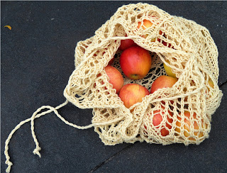  A drawstring bag mesh bag left partially open. The bag has apples inside.
