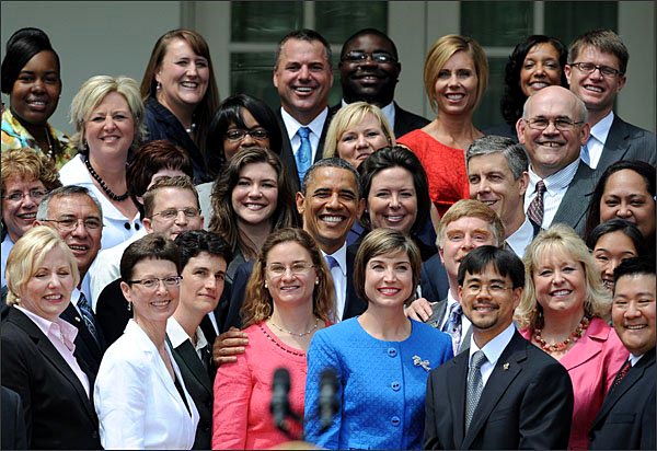 numerous shiny-faced men and women of various ages and races surround President Barack Obama in an informal group photo