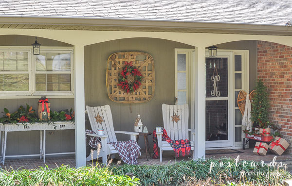 white wicker table, adirondack chairs, red radio flyer wagon with Christmas decor on front porch