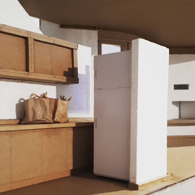 Detail of the kitchen of a cardboard model of The Paterson House designed by Enrico Taglietti, with bags of groceries on the bench.