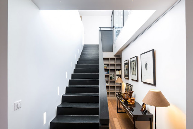 Simple black stairs side by side with pictures and a book shelf decoration.