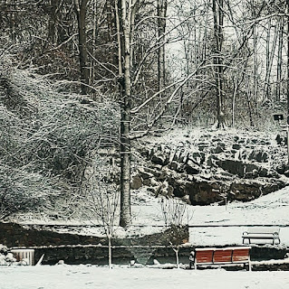 fountain with rocks on a hill in the background in snow