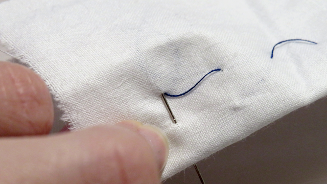 Alfiler en perpendicular a hilos flojos por la parte trasera
