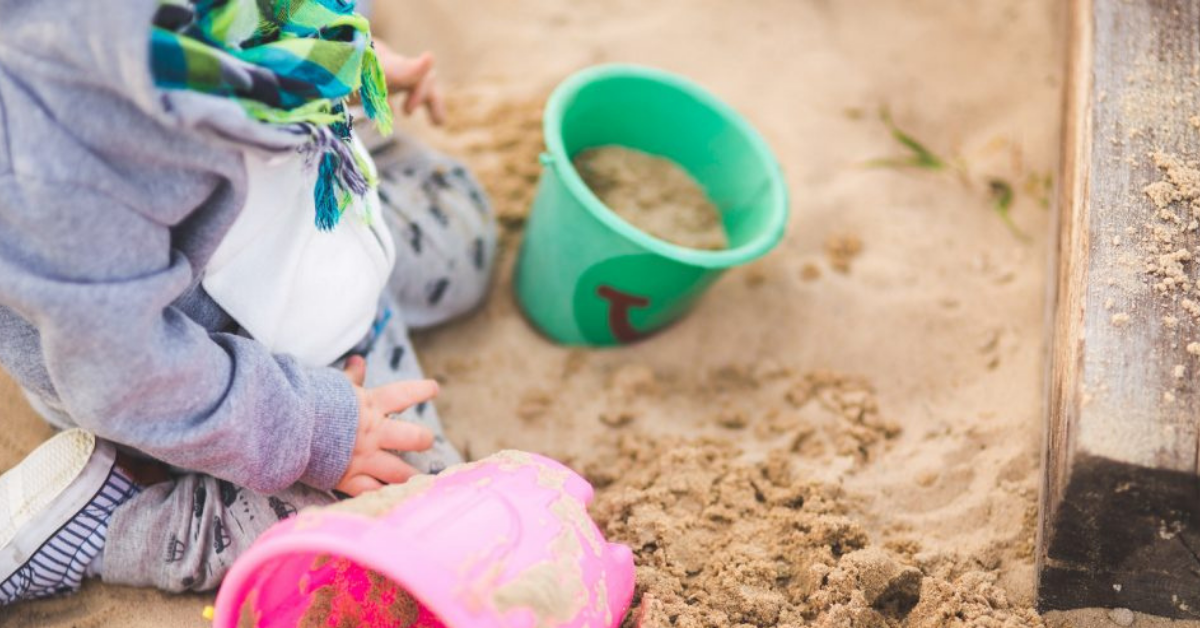 child playing with buckets of sand