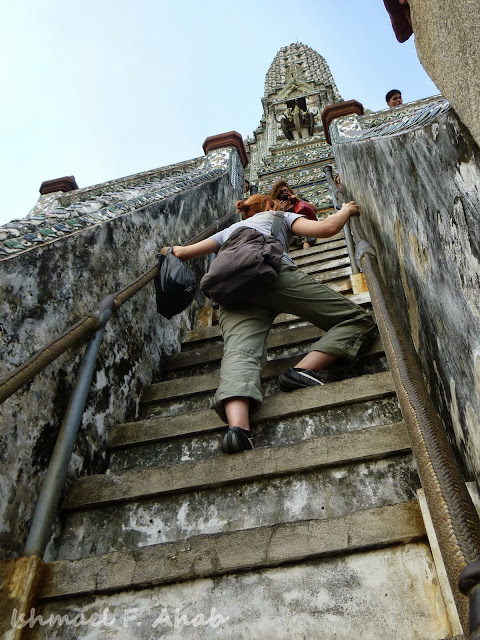 A tourist climbing up the steep steps of Wat Arun