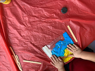 child's hands pressing on paint filled ziplock bag with heart shape