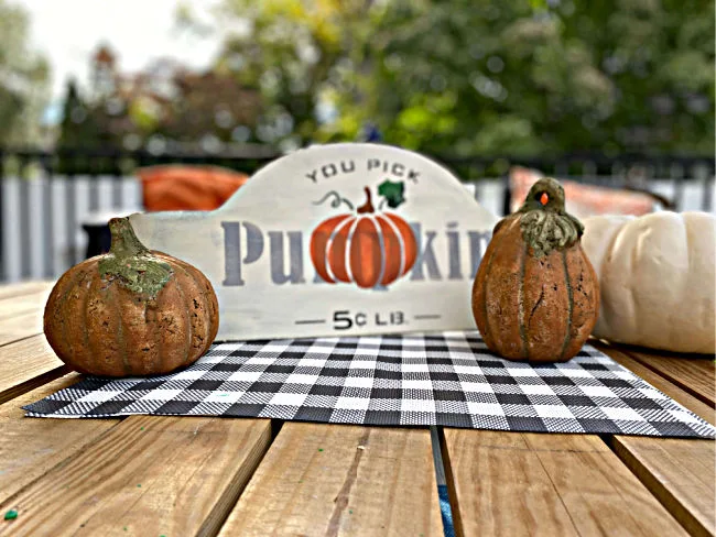sign on outdoor table with pumpkins