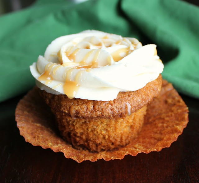 All of the delicious flavors of carrot cake in cupcake form! These beauties are the perfect dessert for Easter, Thanksgiving and every day in between! carrot cake cupcake with wrapper pulled down, caramel frosting on top and drips of caramel topping