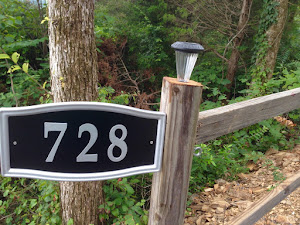 A close up of a fence light and the address plate.