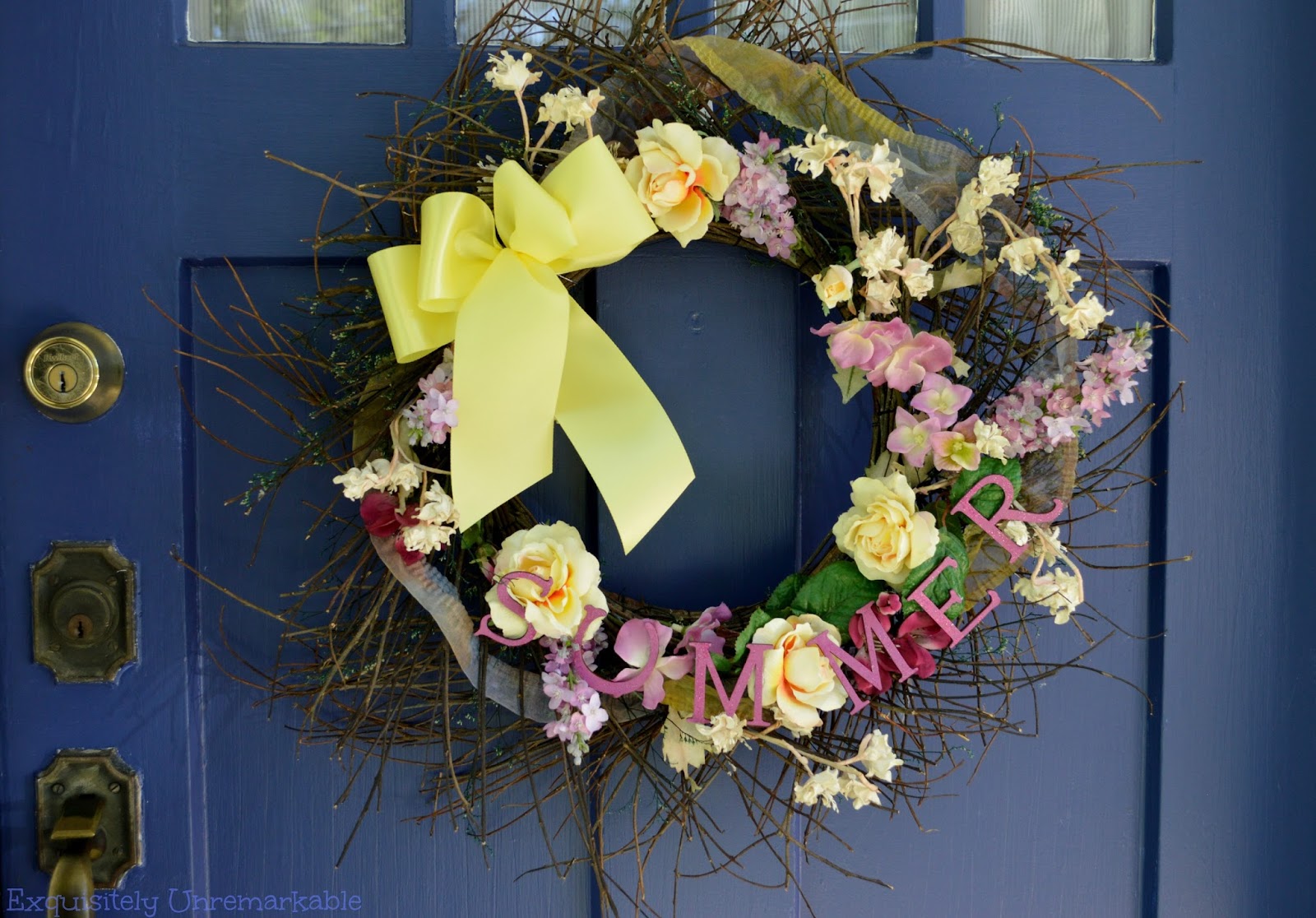 Bright floral summer wreath with a yellow bow on a blue door