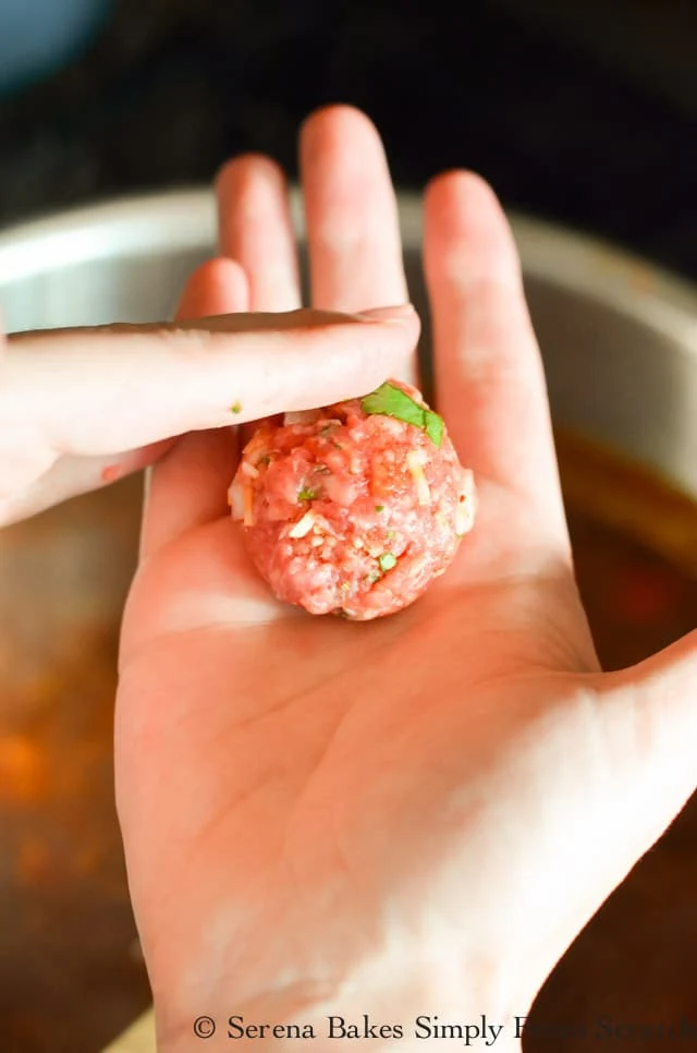 Mexican Meatball meat mixture being rolled between 2 hands.