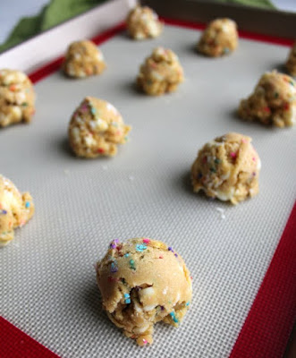 scoops of cookie dough on silicone mat lined baking sheet