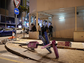 pole with directional signs for pedestrians that was bent down to the ground by protestors in Hong Kong