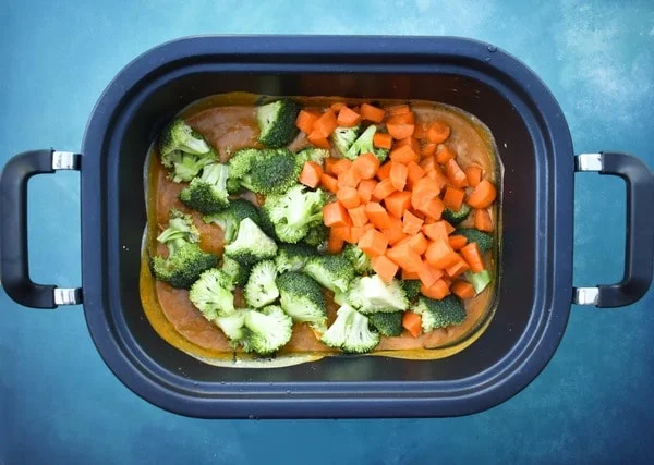 Broccoli and carrots added to the slow cooker pot