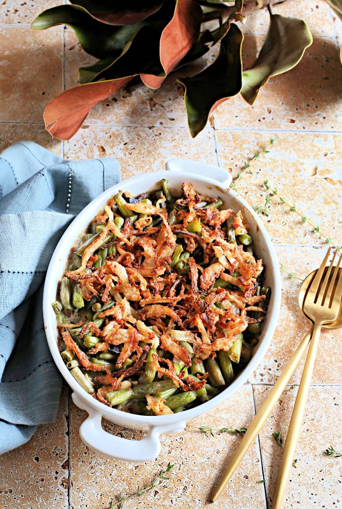 Recipe for a green bean casserole made with mushrooms, caramelized onions and a creamy béchamel sauce, topped with homemade crispy onions.