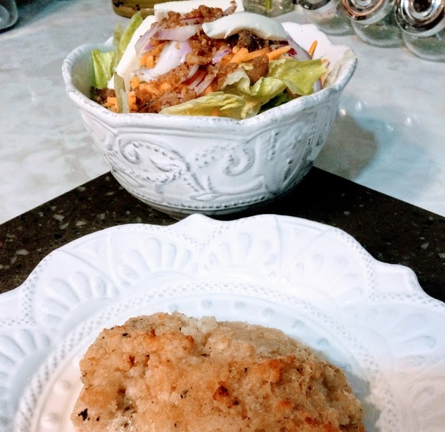 Baked Mahi Mahi arranged on white scalloped plate with salad in white scalloped stoneware bowl  