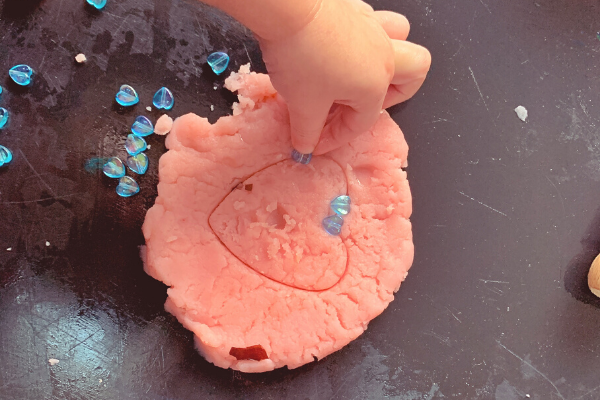 putting heart beads into pink playdough on the tuff tray