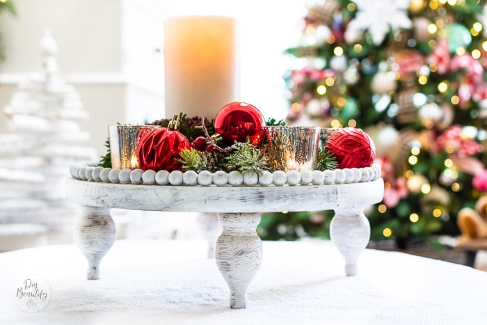 white round beaded wood tray styled with ornaments and candles