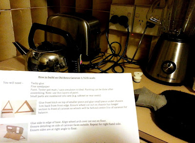 A set of kit instructions in front of a kettle and hot water bottle on a kitchen bench.