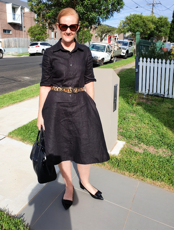 photo of a lady wearing a wrinkled linen shirt dress in the front yard of a house
