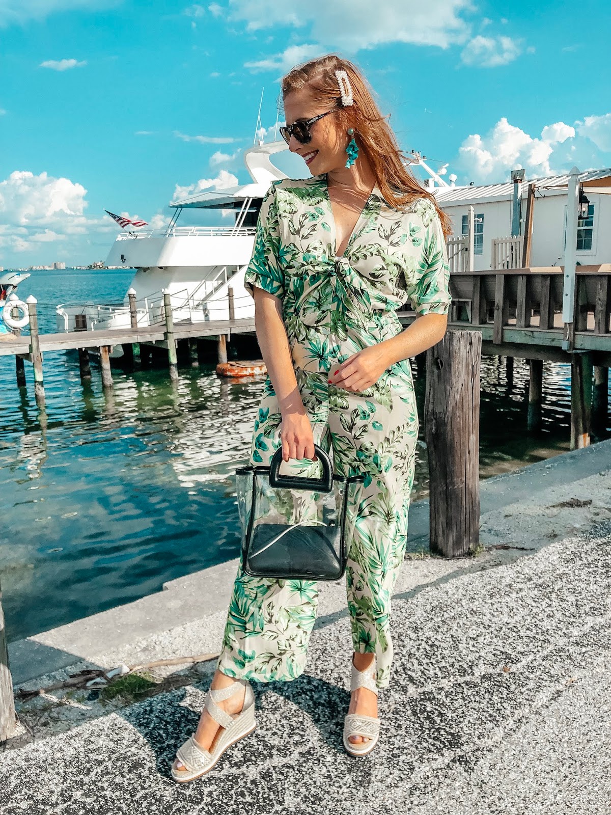tampa blogger affordable by amanda wearing a yellow and green palm print jumpsuit from bealls outlet. she is walking in front of the starlite cruise ship. she is holding a clear bag from Target and wearing platform Tommy Hilfiger espadrilles from bealls outlet. 