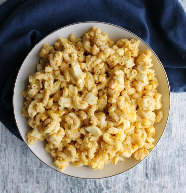 All of the flavor of beloved deviled eggs with less pressure to make them look perfect. This deviled egg pasta salad is perfect for picnics, BBQs or just because. Looking down at a serving bowl of creamy deviled egg pasta salad