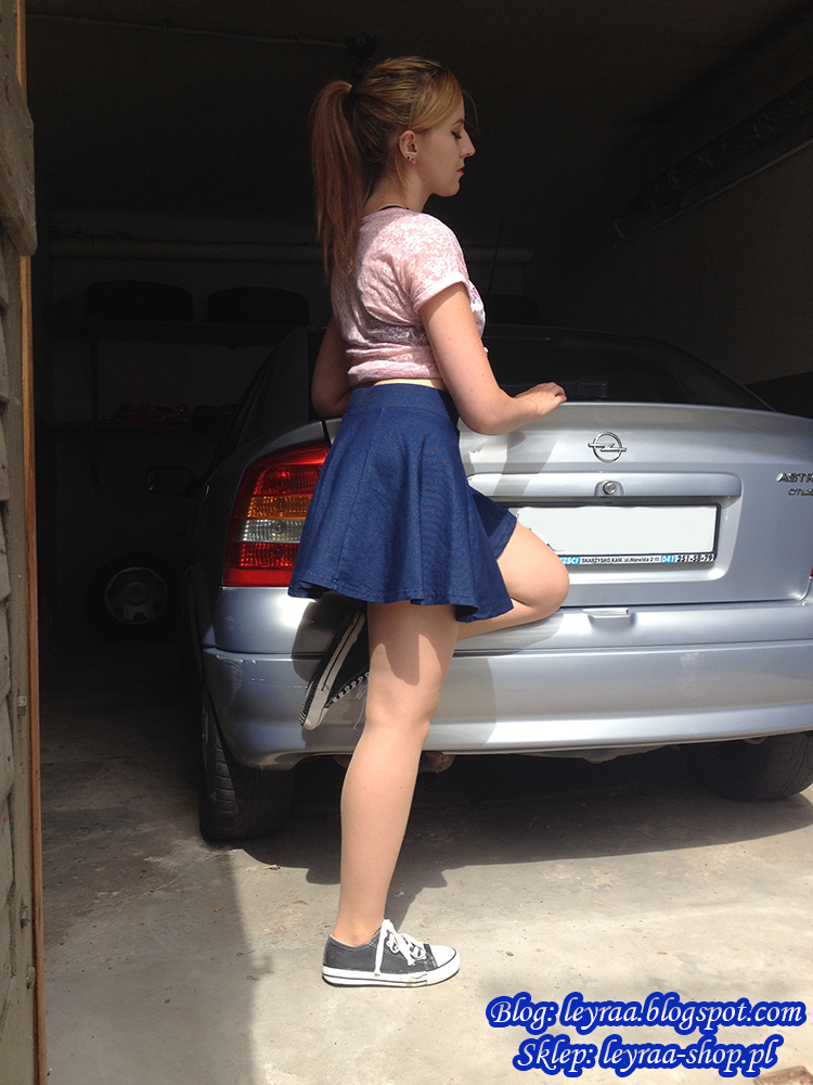 Pastel pink printed t-shirt, slightly translucent tied with a knot, black bra, flared denim skirt, black sneakers