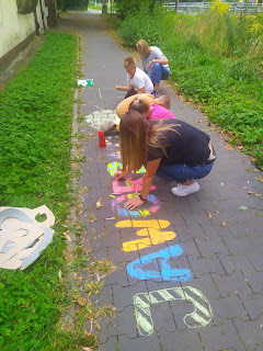 Dzieci rysujące kredą napis Jaworzno na chodniku