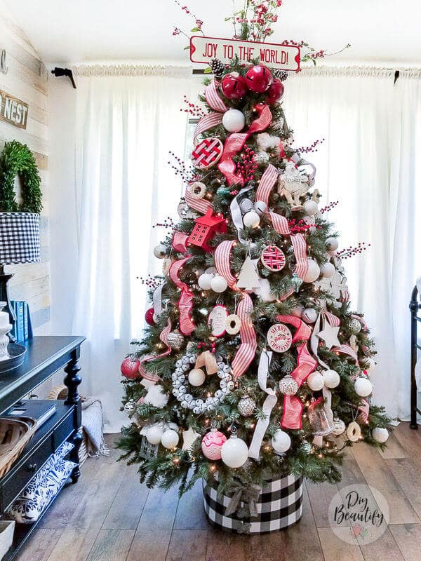 red and white striped Christmas tree decorated with ribbons, a metal sign topper and buffalo check tree collar