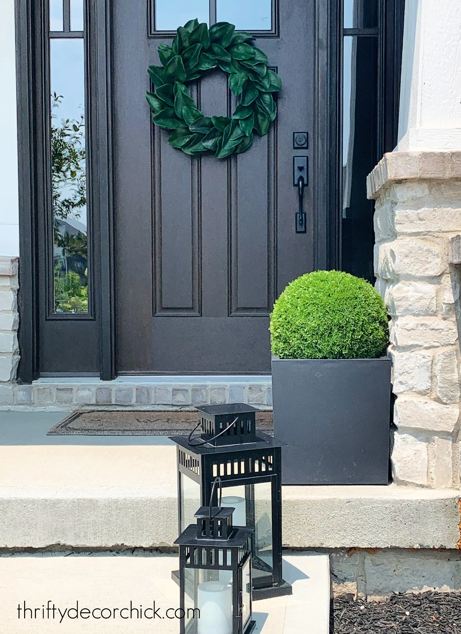 black planter with green boxwood on porch