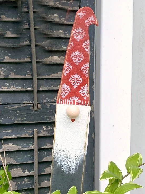 Garden gnome sitting in planter in front of shutter