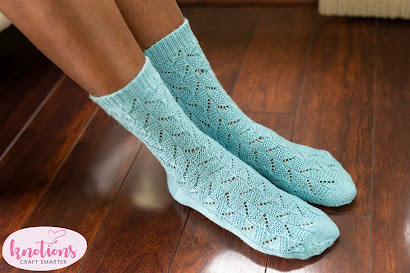 A person wearing a pair of pale blue fingering-weight lace socks