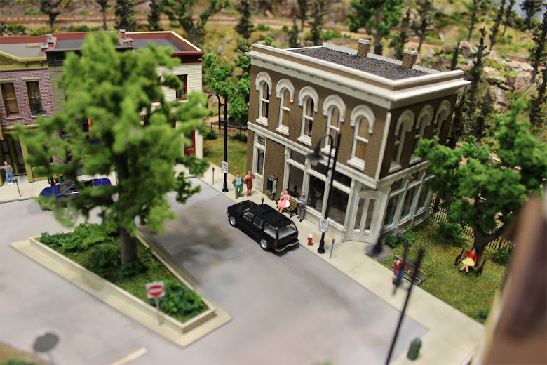 Sidewalk scene in front of a Other Corner Café kit including figures, meters, benches, fire hydrants and vehicles