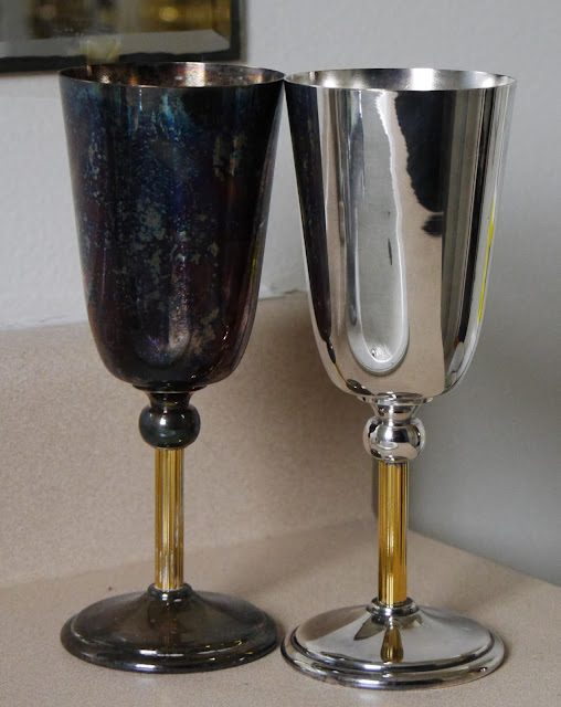Two silver cups sit side by side on a bathroom counter. One is heavily tarnished, the other is bright and shiny.
