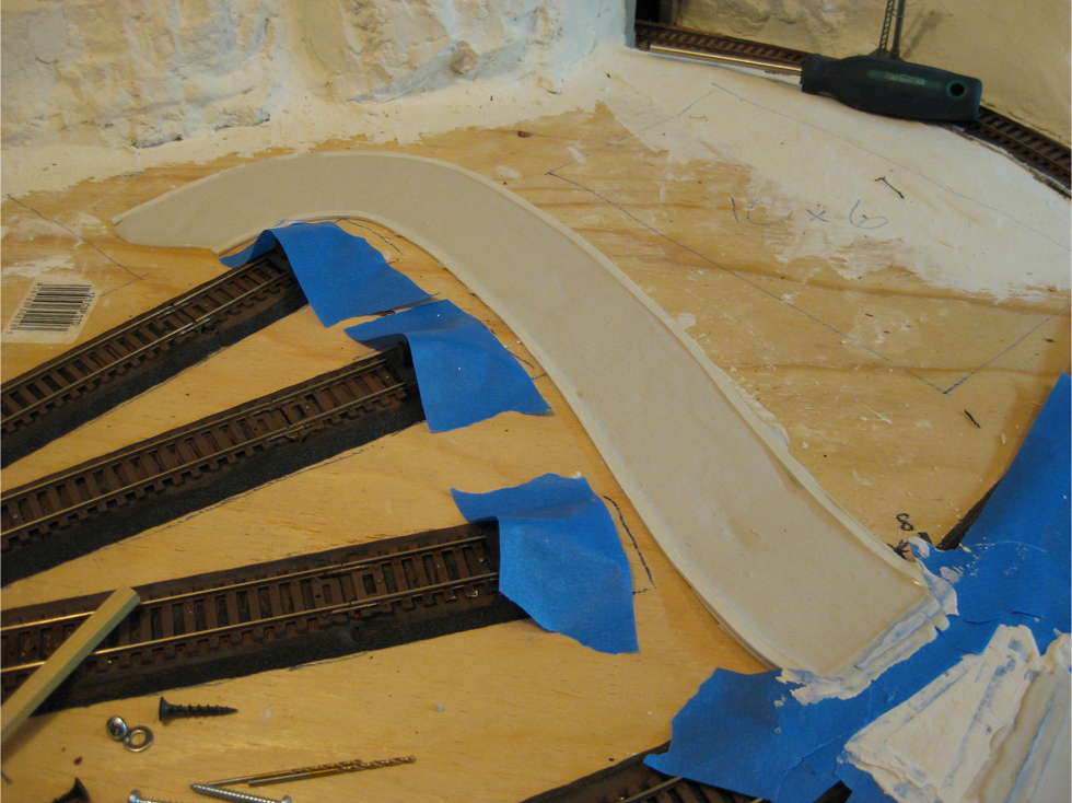 First layer of Woodland Scenics Smooth-It road plaster being applied to forms made from double sided foam tape