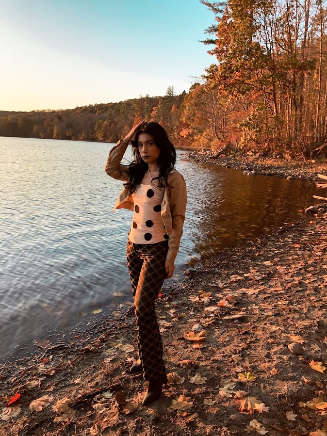 Lina Mayorga Sustainable crop top, Versace logo pants, brown beige medusa logo, Jacquemus polka dot top strapple top, beige top with black dots, trees and leaves and a lake in the background, fall mood, North Salem, NY 2020