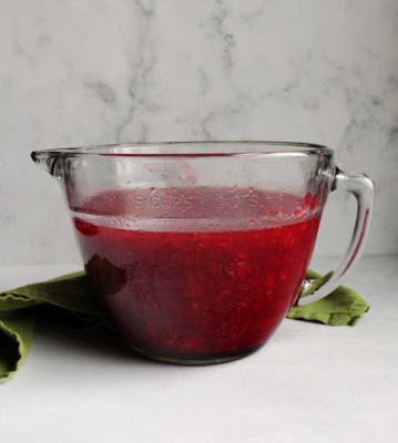 mixing bowl filled with cherry jello mixture glass mixing bowl with jello, cherry and pineapple mixture ready to chill