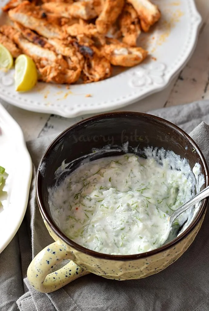 a white and black bowl with easy tzatziki sauce and a plate with shredded chicken