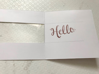 An open square card and on the inside is stamped the word 'hello'